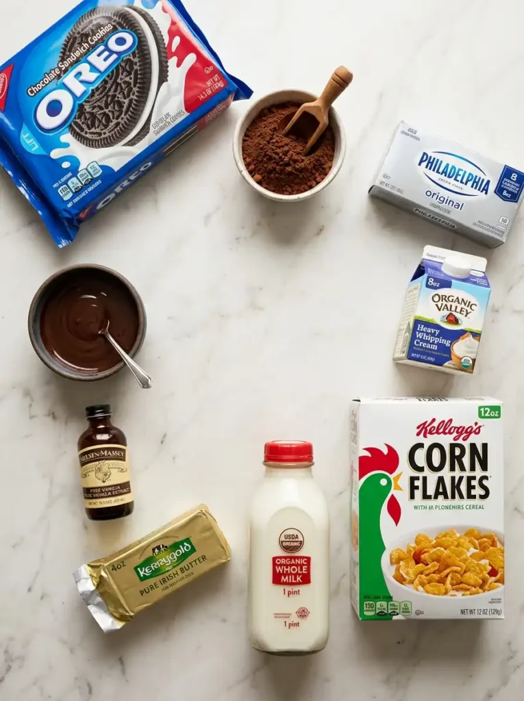 "Flat lay ingredients for lazy cat cake recipe: chocolate cookies, cocoa powder, cream cheese, heavy cream, Corn Flakes cereal, milk, and butter"