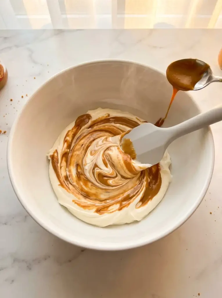 Folding warm Biscoff cookie butter spread into creamy mascarpone cheese for tiramisu filling
