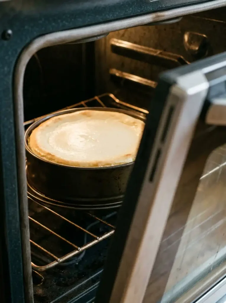 Baked cheesecake with set edges and a slightly soft center before its gradual oven rest.